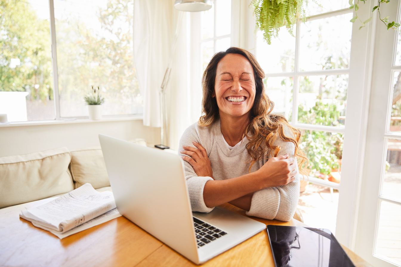 Laughing mature woman working online from home